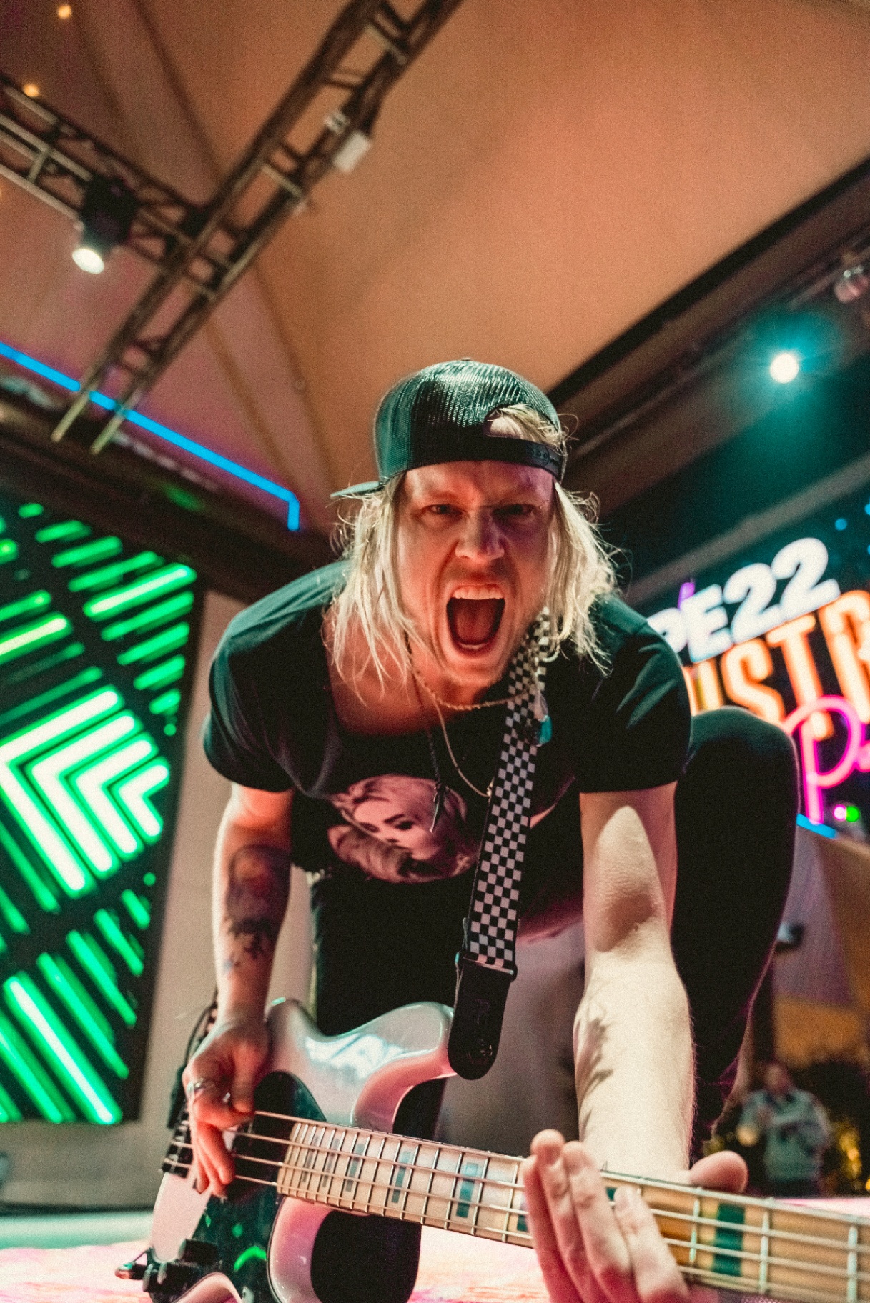 Bassist screaming on stage with neon backdrop