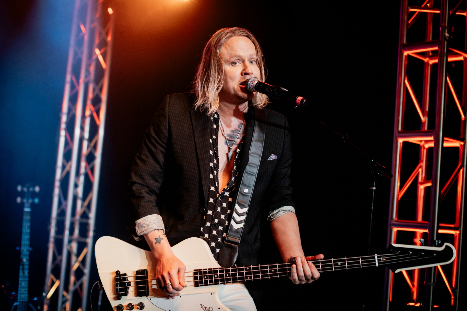 Bryce singing into the mic with white bass in hand