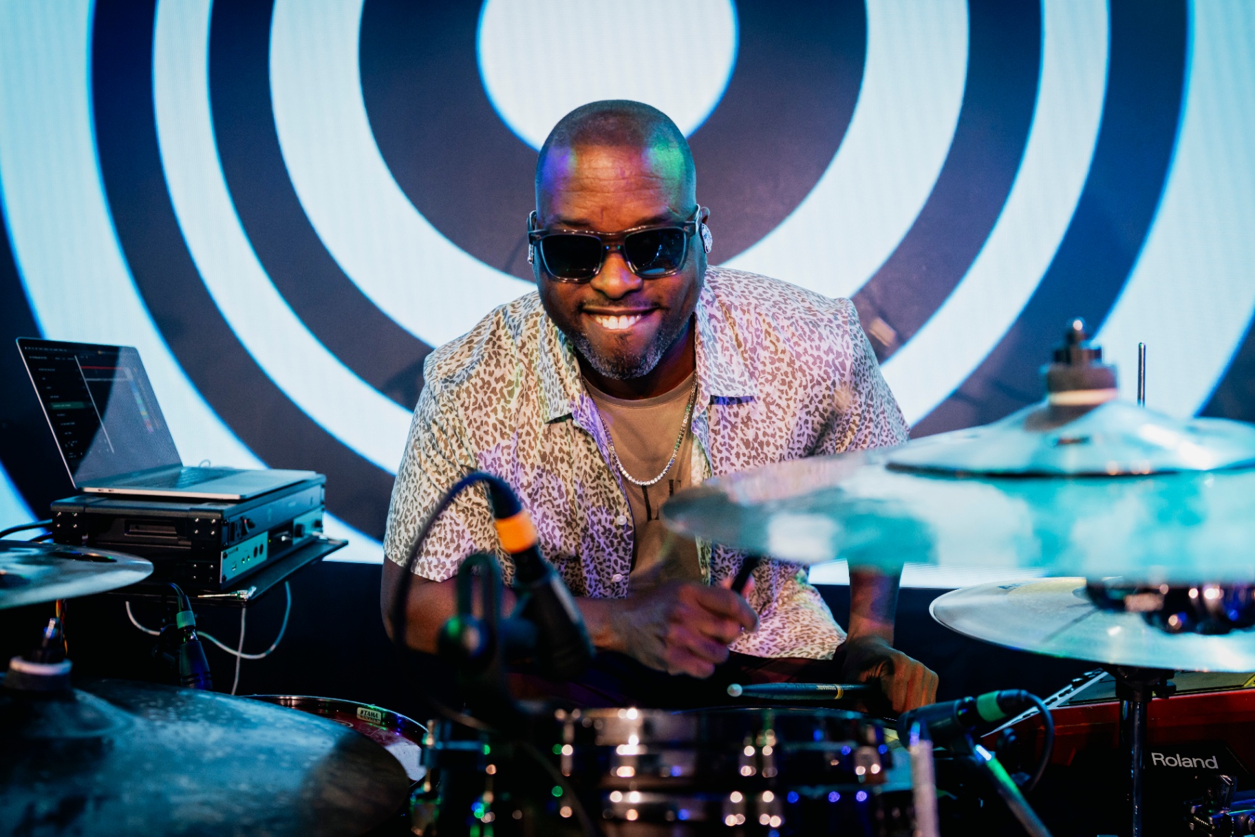 Keith smiling behind the drums in front of concentric circles